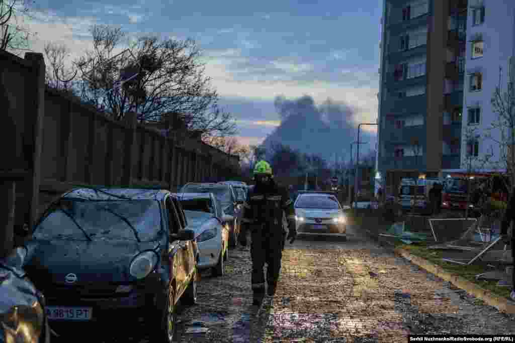 Рятувальники на одному із місць влучання в Києві, на задньому плані видно дим від влучань в інших локаціях столиці. 16 квітня 2026 року