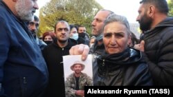 ARMENIA -- A woman holds a photograph of a serviceman who remains unaccounted for during a rally in Yerevan, November 24, 2020