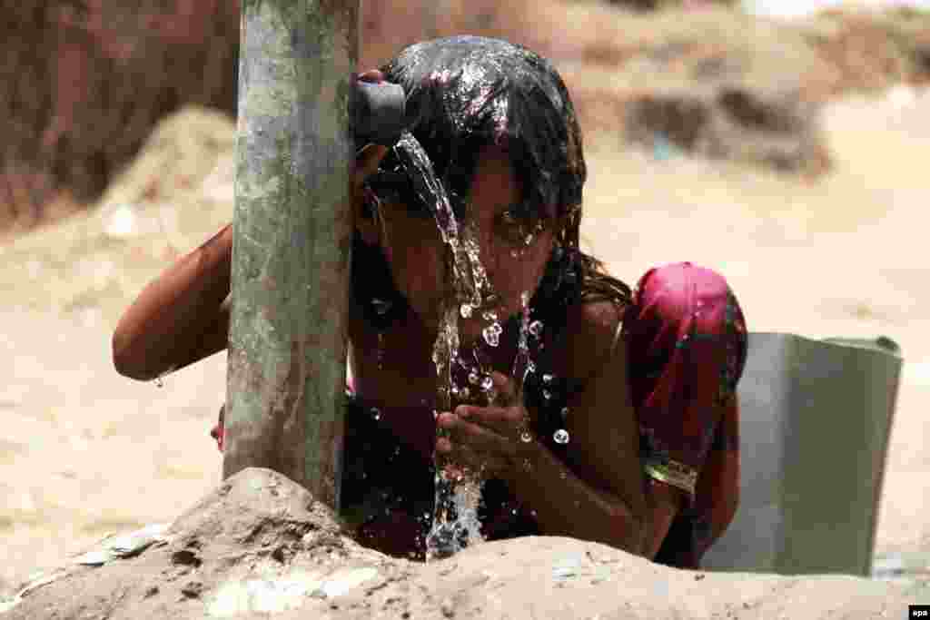 A girl cools off under a community tap on the outskirts of Hyderabad, Pakistan, on June 1, as temperatures went up to 53 degrees Celsius in the country. (epa/Nadeem Khawer)