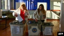 Two women vote during the presidential elections and a referendum on joining the European Union at a polling station in Hirbovat, Moldova, on October 20.