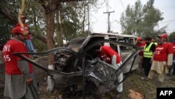 Volunteers examine the wreckage of a vehicle after a suicide bomb attack in Peshawar on February 15.