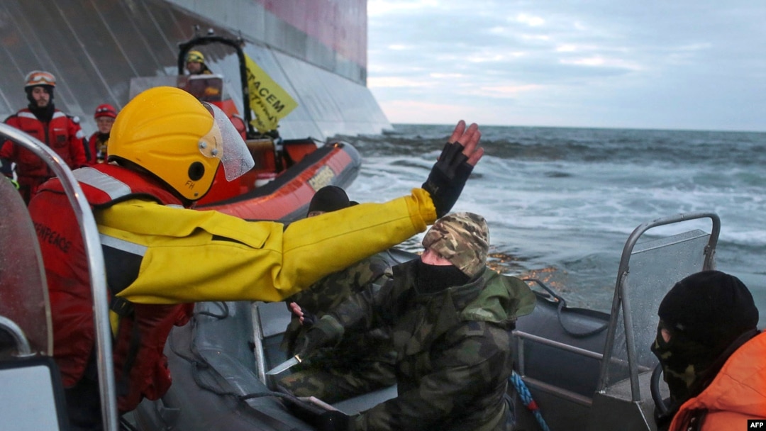In a Greenpeace handout photo taken on September 18, a Russian Coast Guard officer (center) wields a knife at an activist during a Greenpeace attempt to climb Gazprom’s "Prirazlomnaya" Arctic oil platform in the Pechora Sea.