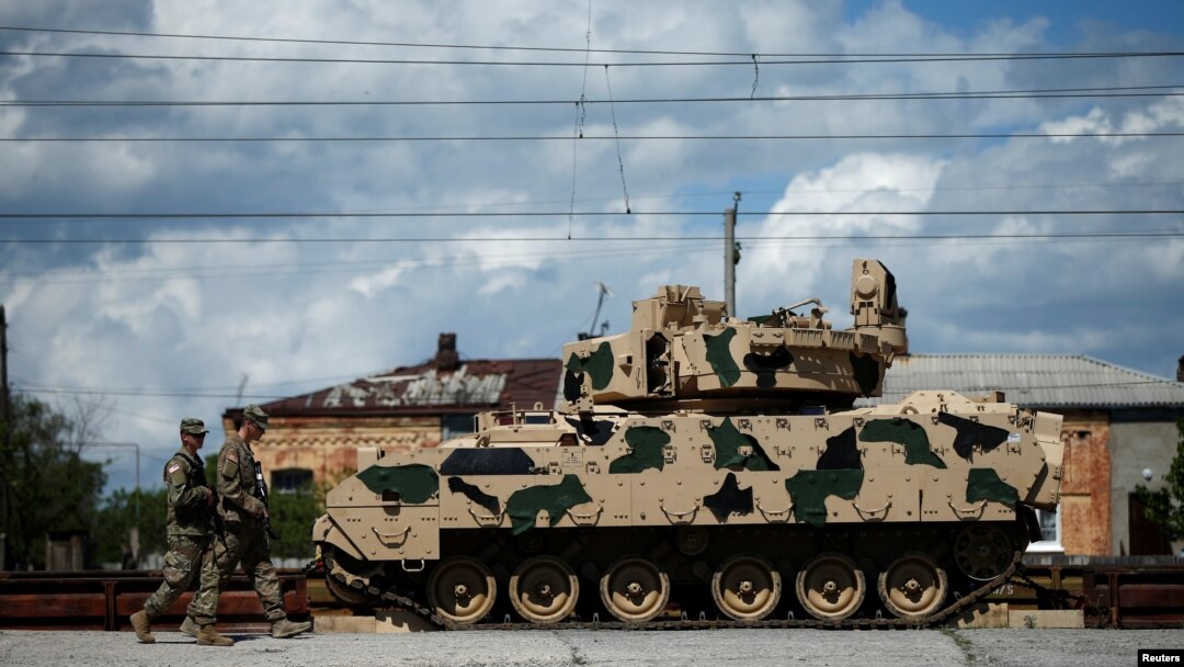 U.S. servicemen walk past a Bradley infantry fighting vehicle as they arrive for the joint U.S.-Georgian exercise Noble Partner 2016 in Vaziani.