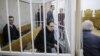 The three men on trial look on from the defendants' cage in a courtroom in Minsk on December 18.