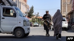 یک زن در حال عبور از کنار یک سرباز طالبان در شهرک جبرئیل هرات
