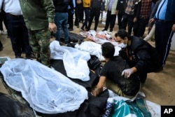 A man is comforted as he sits next to the body of a loved one killed in the terrorist explosions in the Iranian city of Kerman on January 3.