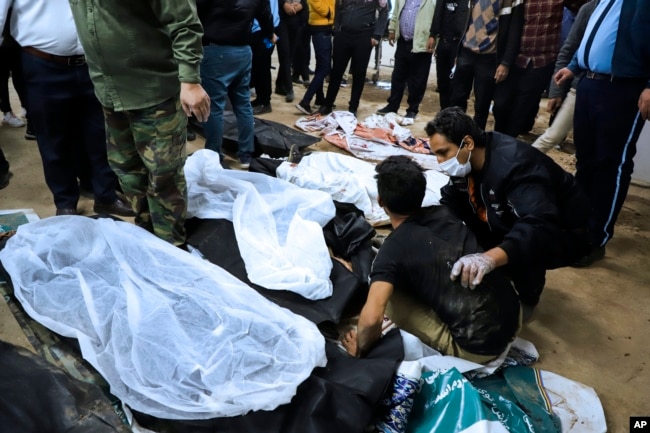 A man is comforted as he sits next to the body of a loved one killed in the terrorist explosions in the Iranian city of Kerman on January 3.