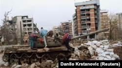 Children play on a damaged tank in front of a ruined building in Sarajevo's Kovacici district in February 1996. 
