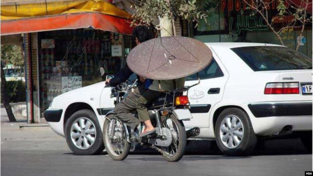 An Iranian man on a motorcycle carries a satellite dish. (file photo)