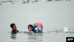 Migranții au înotat - unii cu colacul de salvare - pe lângă o barieră de frontieră cu Marocul pentru a intra în enclava spaniolă Ceuta din Africa de Nord.