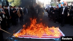 People watch as a U.S. flag is set on fire during the 42nd anniversary of the takeover of the U.S. Embassy in Tehran on November 4.