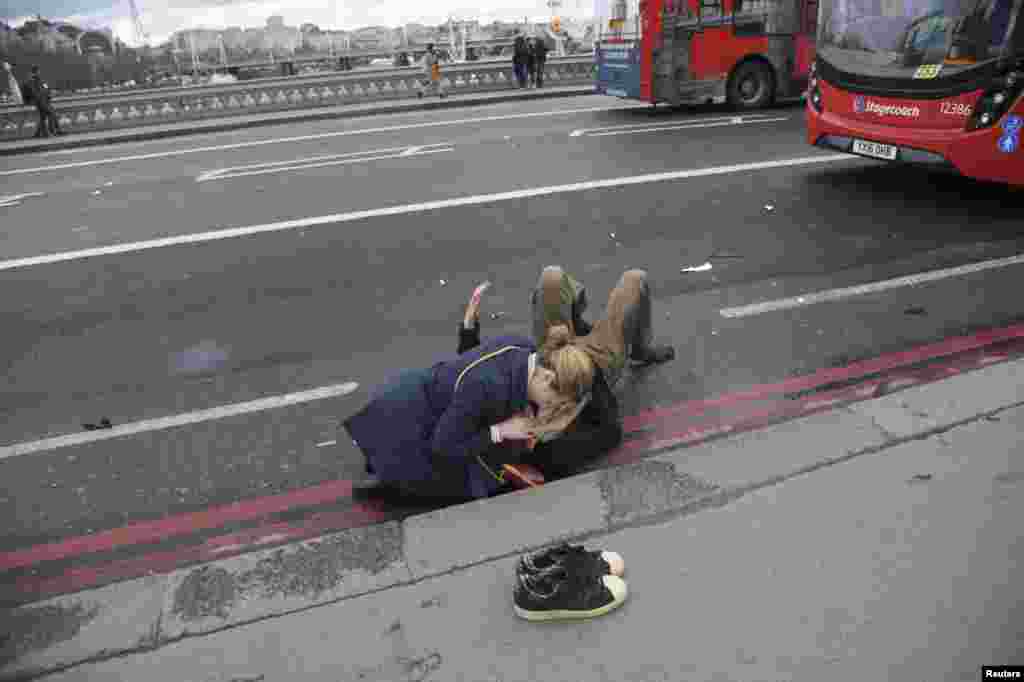 A woman assists an injured person after the incident on Westminster Bridge, next to the Houses of Parliament.&nbsp;