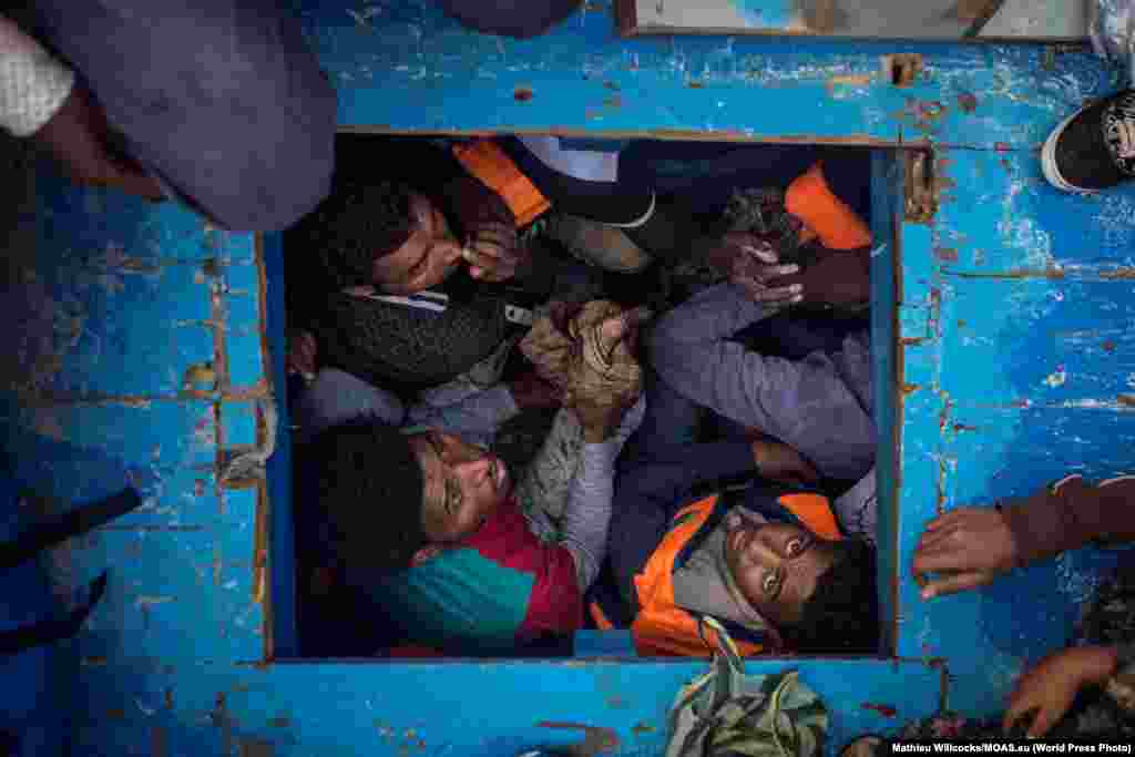 Третий приз в категории &quot;Новости&quot;: беженцы из Эритреи в деревянной лодке, пересекающей Средиземное море. В момент съемки на борту было около 540 человек. Фото &ndash; Мэтью Уиллокс.