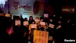 Një grup protestuesish duke kujtuar viktimat që vdiqë nga zjarri në Urumqi të Kinës.