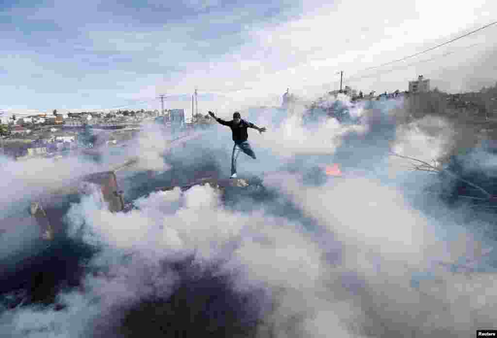 A Palestinian protester jumps as tear gas fired by Israeli soldiers rises during clashes in Jalazoun refugee camp near the West Bank city of Ramallah on January 31. (Reuters/Mohamad Torokma)