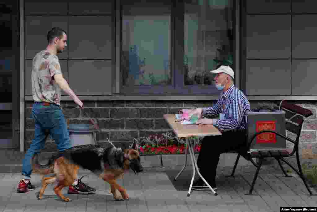 Un alegător din Sankt-Petersburg a venit împreună cu câinele său la o secție de votare deschisă în aer liber.