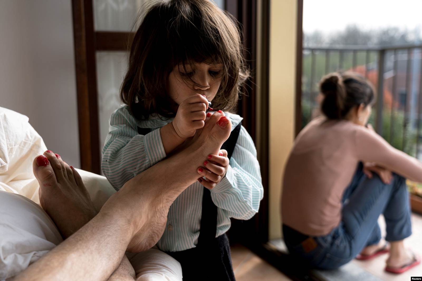  Mësuesi italian Marzio Toniolo duke fotografuar vajzën e tij dyvjeçare Bianca, duke ia lyer thonjtë, derisa nëna e vogëlushes rri në ballkon.