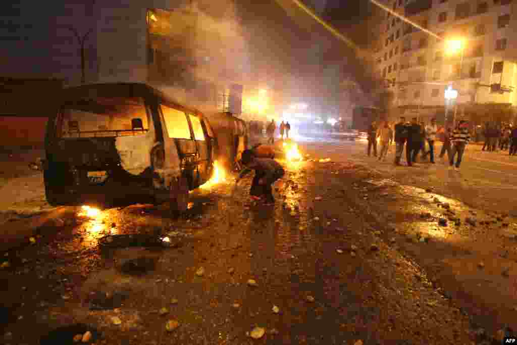 Egyptian demonstrators fuel the fire next to burning police vehicles in Cairo.