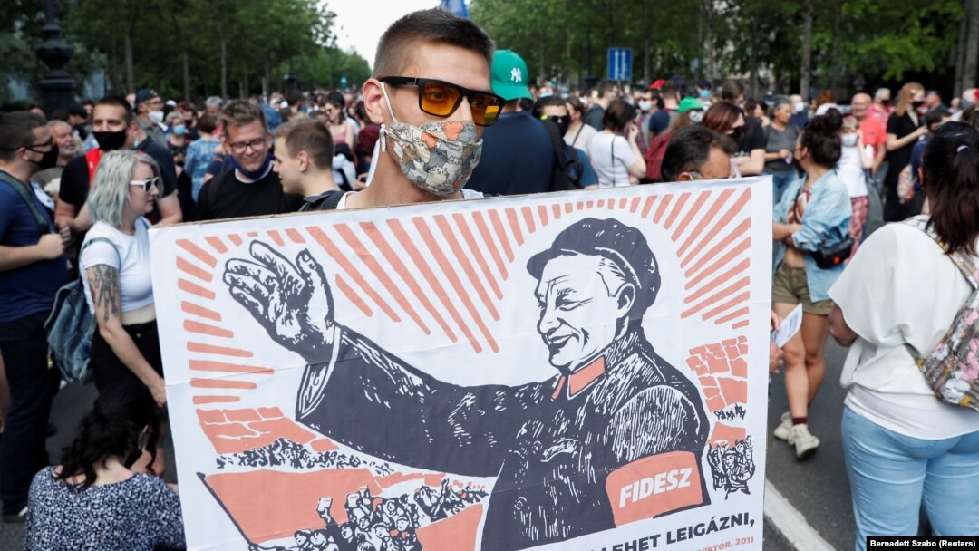 Un protestatar ține o pancardă cu imaginea prim-ministrului Ungariei, Viktor Orban, ilustrat ca un lider comunist din China, 5 iunie 2021.