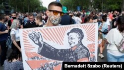Un protestatar ține o pancardă cu imaginea prim-ministrului Ungariei, Viktor Orban, ilustrat ca un lider comunist din China, 5 iunie 2021.