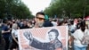 Një demonstrues mban një pankartë që përshkruan kryeministrin hungarez, Viktor Orban, si Mao Tse-Dung gjatë një proteste kundër kampusit të planifikuar të universitetit kinez Fudan në Budapest, qershor 2021.