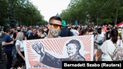 Demonstrant drži plakat na kojem je prikazan mađarski premijer Viktor Orban kao bivši kineski komunistički lider Mao Cedong tokom protesta protiv planiranog kampusa kineskog univerziteta Fudan u Budimpešti u junu 2021.