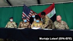 U.S. Brigadier General Vincent B. Barker (R) and Iraqi Staff Major General Mohammad Fadhel Abbas (2-R) attend the handover ceremony of Qayyarah Airfield West, 60km south of Mosul, March 26, 2020