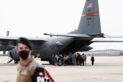 Афганские беженцы, ранее эвакуированные из Кабула, на испанской авиабазе Торрехон-де-Ардос садятся в военно-транспортный самолет США, чтобы лететь дальше в Германию. 26 августа 2021 года