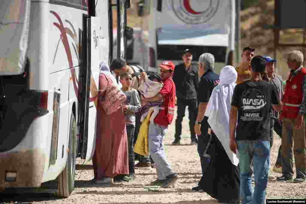 Libanezët e zhvendosur duke hipur në autobusë pasi kaluan më këmbë në pikën kufitare Masnaa.