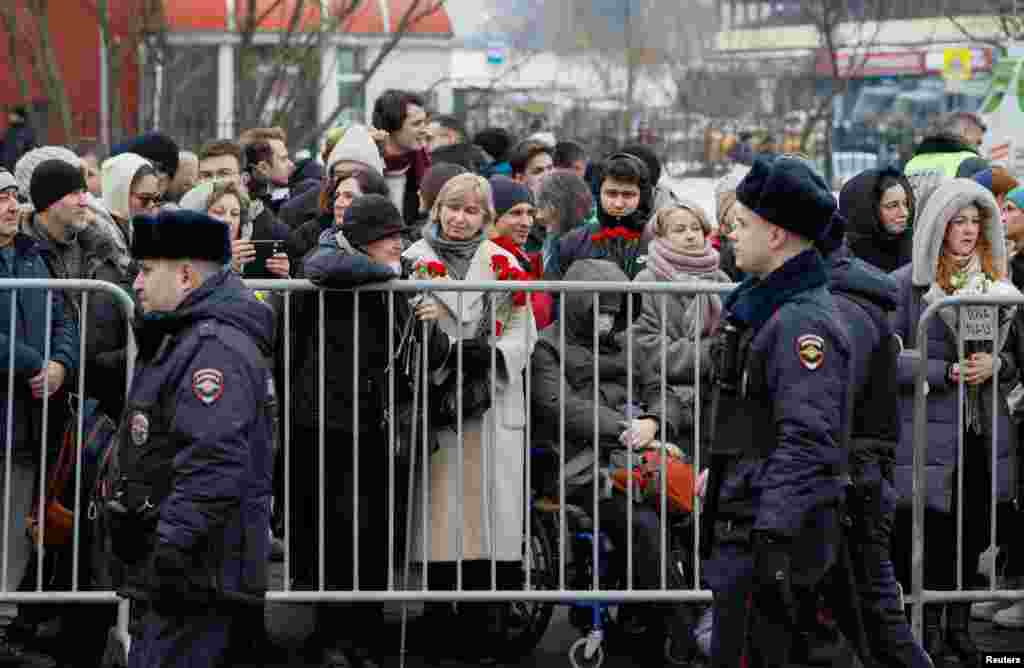 Паліцыянты праходзяць міма людзей, якія прыйшлі да царквы разьвітацца з Аляксеем Навальным