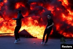 Dy protestues para një zjarri të madh gjatë protestës në Tiranë, Shqipëri, 14 tetor.