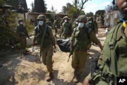 Израильские солдаты несут тело погибшего при атаке ХАМАС на кибуц Кфар-Аза, 10 октября 2023 года