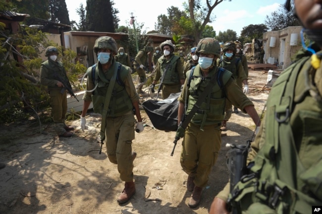 Ushtarët izraelitë mbajnë trupin e dikujt të vrarë në një sulm të Hamasit në Kibbutz Kfar Aza, 10 tetor 2023.