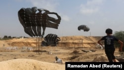 Палестинско момче трча додека пакети со помош се испуштаат од авион, во Деир Ал-Балах, централen дел од Појасот Газа, 12 август 2025