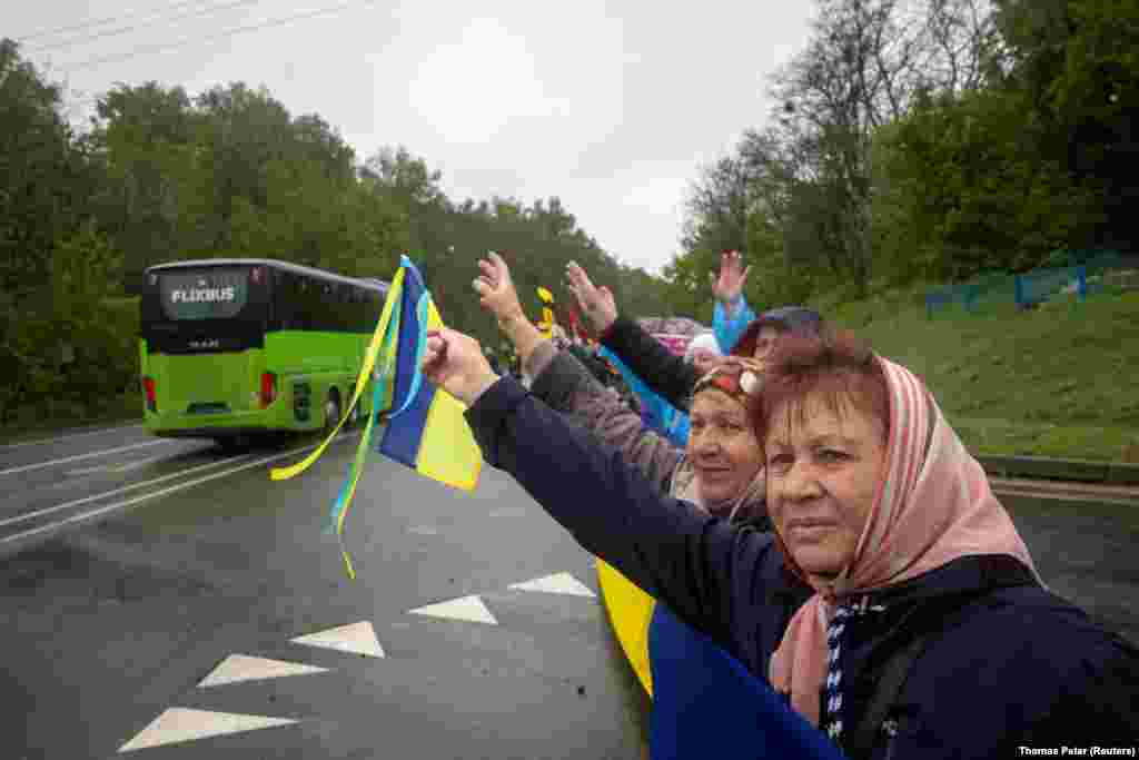 Місцеві жителі зустрічають автобуси, які везуть звільнених з російського полону українських захисників