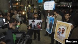 Iranian students hold up pictures of Iranian scientist Mostafa Ahmadi-Roshan, who was killed in a bomb blast on January 11, as they wait for the arrival of the IAEA delegates at Tehran's Imam Khomeini International Airport on January 29.