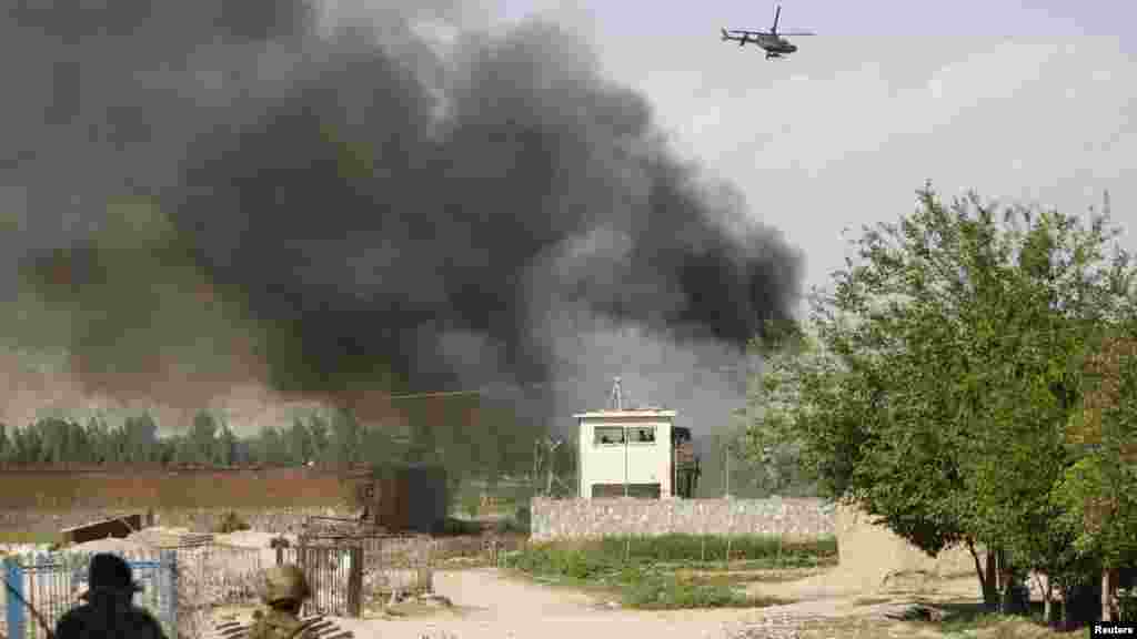 An Afghan National Army soldier keeps watch near the Provincial Reconstruction Team (PRT) as a NATO helicopter flies over the site of an attack in Jalalabad Province on April 15. (REUTERS/Parwiz)