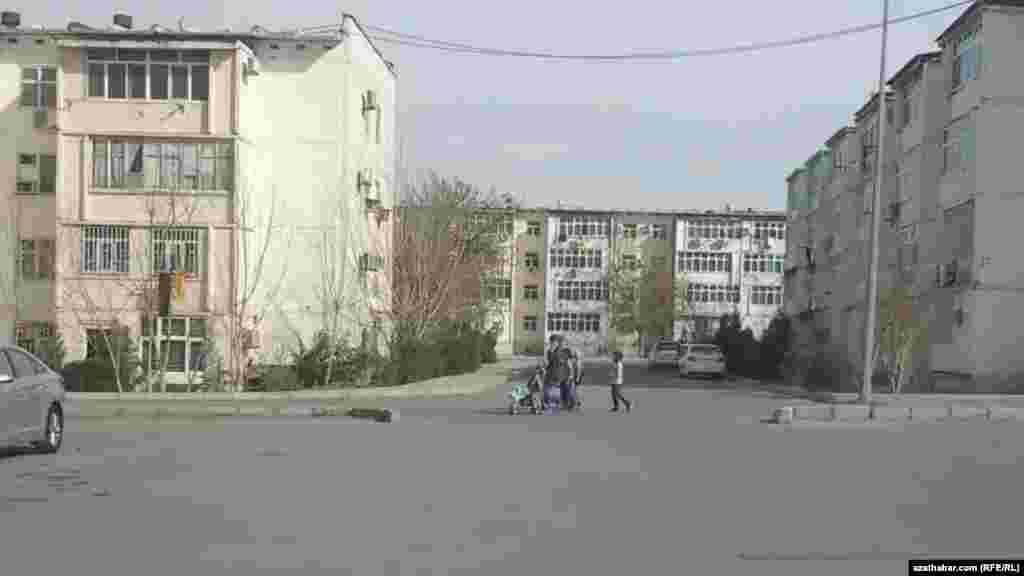 Çagalary bilen köçeden barýan aýal. Aşgabat, fewral, 2021.