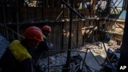 Рабочие стоят возле поврежденной теплоэлектростанции ДТЭК после российской атаки на Украину, 2 мая 2024 года