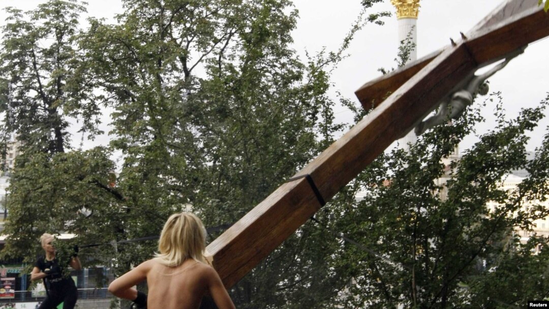 A Femen activist uses a chainsaw to cut down an Orthodox cross erected in memory of the victims of political repression under Soviet dictator Josef Stalin in Kyiv.