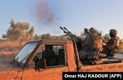 Fighters from the former Al-Qaeda Syrian affiliate Hayat Tahrir al-Sham fire an anti-aircraft gun mounted on a pickup truck in Syria's southern Idlib Province in August 2019.