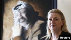 Suha Arafat poses in front of a portrait of her late husband, Palestinian leader Yasser Arafat, before watching a wreath-laying ceremony after her husband's exhumation in the West Bank city of Ramallah in November 2012.