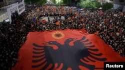Protestuesit e shpalosin një flamur kombëtar shqiptar me emblemën e UÇK-së ndërsa protestojnë kundër një vendimi të gjykatës së Hagës, e cila dënoi ish-udhëheqës të UÇK-së për krime lufte, Prishtinë 20 shtator 2026.
