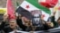 Pro-Islamist demonstrators, holding a Syrian opposition flag and a defaced poster of Russian President Vladimir Putin, shout slogans during an anti-Russian protest in Istanbul, Turkey, on November 27.
