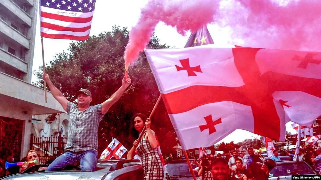 Protesters waive the Georgian and U.S. flags during a motorcade rally in Tbilisi on June 24.