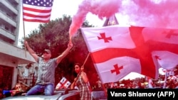 Protesters waive the Georgian and U.S. flags during a motorcade rally in Tbilisi on June 24.