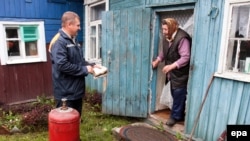 An employee of the Mingas Belarus gas company speaks with a woman as he makes a gas delivery to her house in a Minsk suburb today.