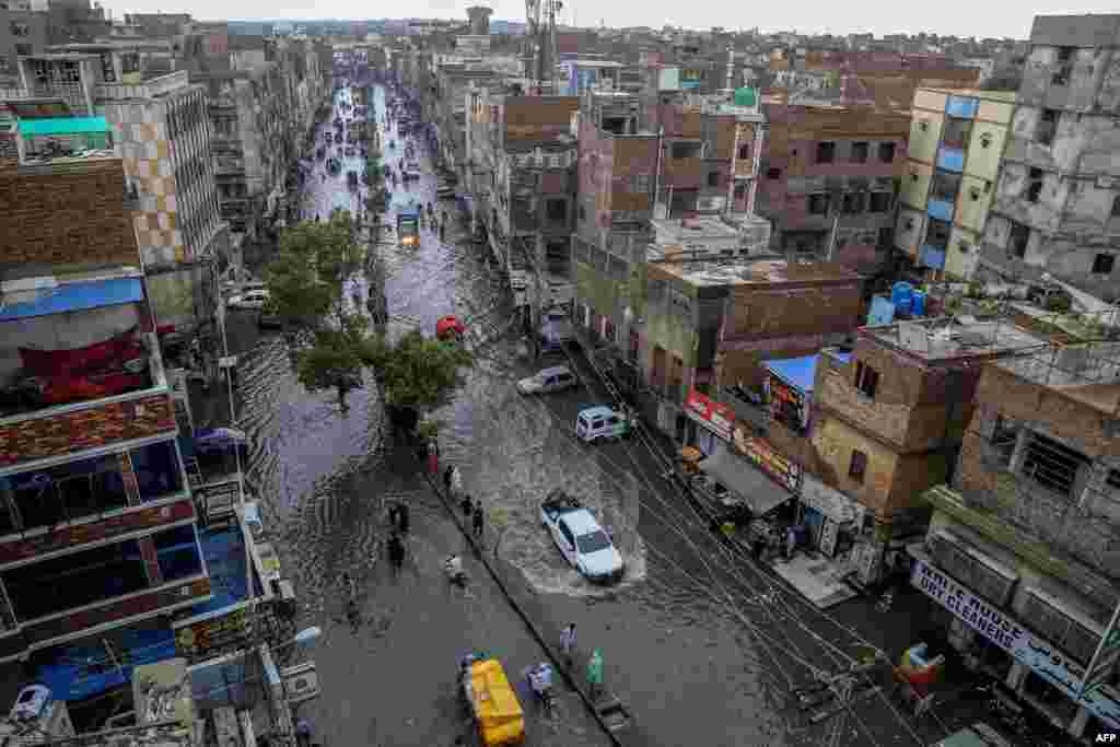 Pakistani commuters make their way through a flooded street during heavy monsoon rains in Hyderabad.
