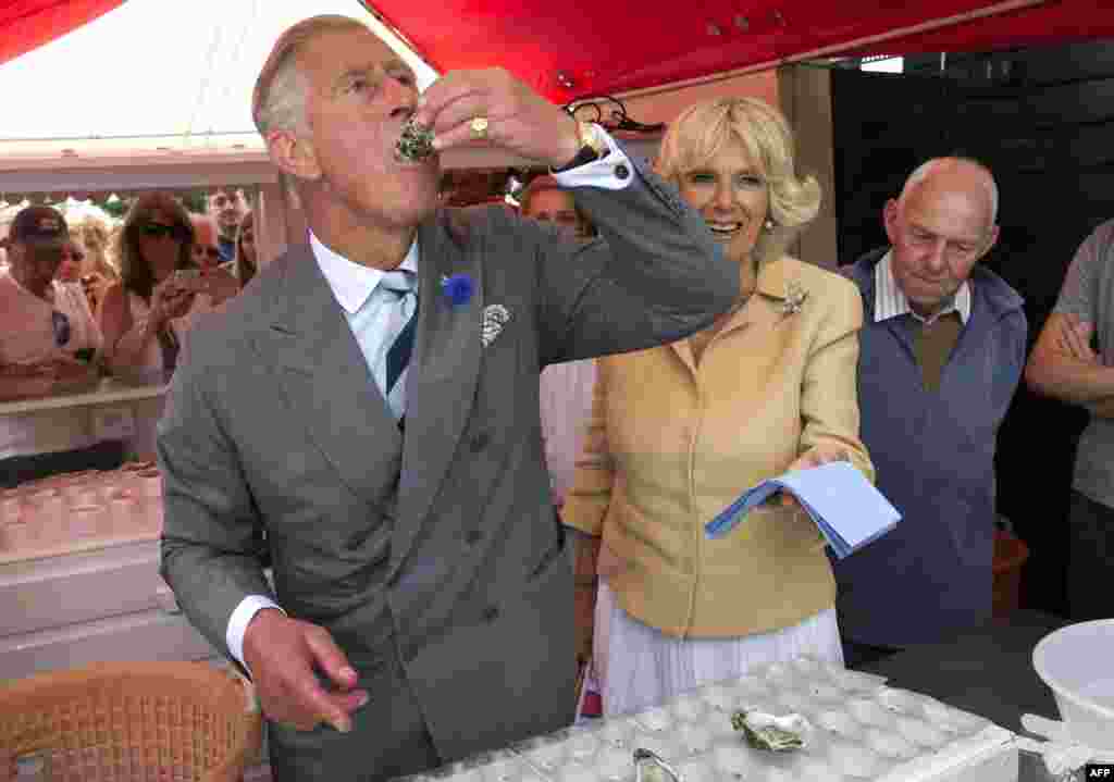 Britain&#39;s Prince Charles samples a raw oyster as Camilla, the Duchess of Cornwall, looks on during a visit to the Whitstable Oyster Festival in Whitstable, England. (AFP/Arthur Edwards)