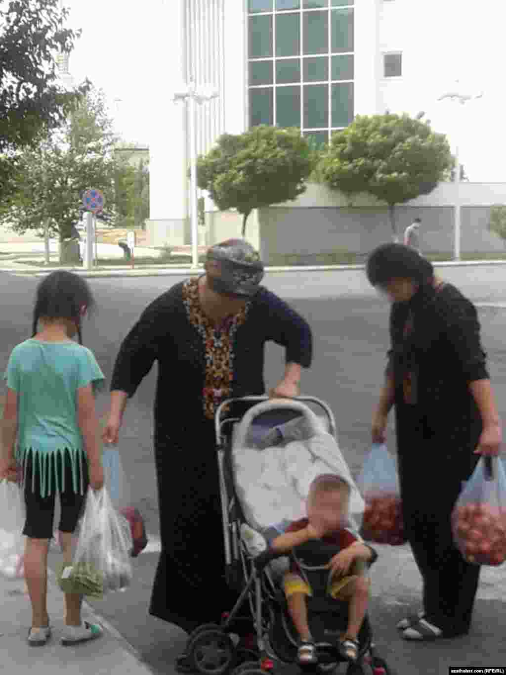 Aşgabat. Çagalary bilen dükandan gelýän aýal. Awgust, 2020.